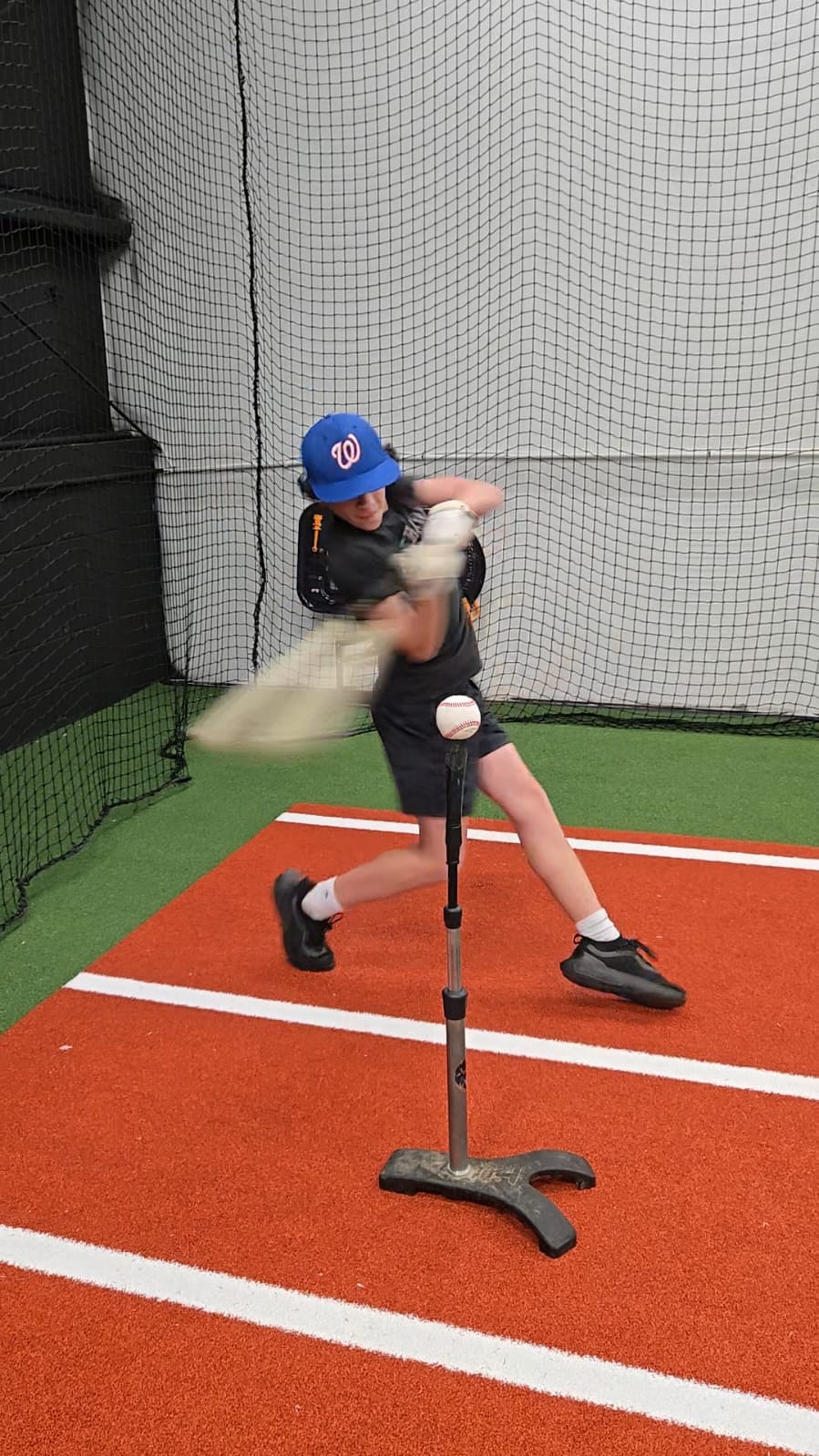 A boy playing baseball and hitting a ball with force
